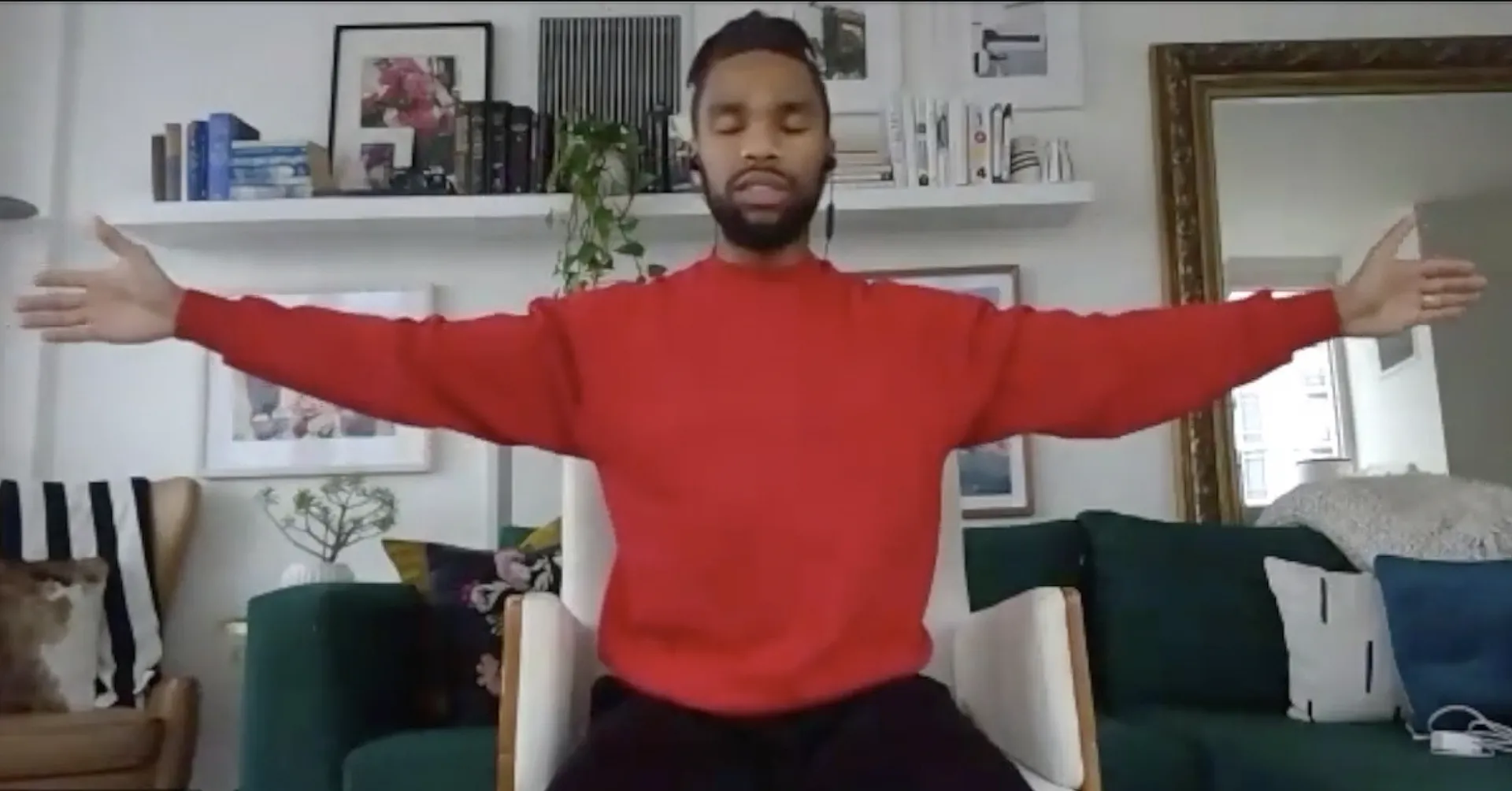 Man sits in a chair with arms stretched out to his sides during an Office of Work/Life mid-day stretching class.